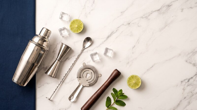 Shaker, doseur, cuillère à mélange, passoire et pilon posés sur du marbre Image